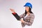 Serious female engineer in hard hat examines the plan and shows with his hand to the side on a white background.