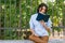 Serious female model focused on reading, sits at wall in the park. Concetrated student prepares for coming session at college.