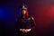 Serious female police officer is posing for the camera against a black background with red and blue backlighting.