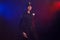 Serious female police officer is posing for the camera against a black background with red and blue backlighting.