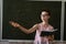 serious female teacher explain math formulas in university beside blackboard