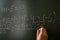 serious female teacher explain math formulas in university beside blackboard