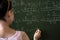 serious female teacher explain math formulas in university beside blackboard