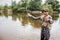 Serious fisherman stands on shallow an waving with fly-fishing. Also he has a spoon in other hand. Guy is looking to the