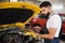 Serious focused man car technician mechanic repairing car problem of engine, during system checking