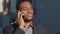 Serious focused millennial African American businessman standing outdoor talking on phone, young mixed race entrepreneur