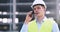 Serious foreman in protective helmet talking to contractor on smartphone standing on construction site