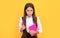 Serious frown child hold school book and pen yellow background, learning