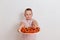 Serious full eight-year-old boy holds a plate of ripe strawberries