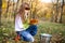 Serious girl in the forest with leaves and bucket