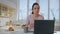 Serious girl freelancer sitting kitchen with laptop close up. Woman making notes