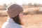 A serious girl in a knitted hat stands against a background and a coat against the backdrop of an autumn pale river landscape