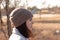 A serious girl in a knitted hat stands against a background and a coat against the backdrop of an autumn pale river landscape