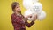 Serious girl pointing at recycle symbol on white balloon standing at yellow background. Portrait of confident slim