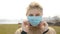 Serious girl puts on a medical mask. Polluted environment. Smoking field