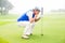 Serious golfer kneeling on the putting green