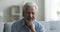 Serious grey haired older man sitting on home sofa