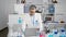 Serious grey-haired young hispanic man a scientist, engrossed in his work while sitting at laboratory table with laptop, deeply