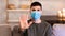 Serious guy in face mask gesturing stop sitting on couch