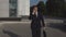 Serious handsome businessman in black suit with diplomat talking on smartphone and hurrying to meeting against the