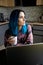 Serious hipster woman with blue hair thinking with laptop on kitchen