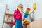 serious housewife in colorful clothes with dusting brush talking on retro telephone