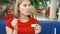 Serious hungry young woman in red t-shirt sitting in cafe eating french fries dipping it in sauce