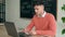 Serious indian student has video chat at pc at desk in classroom writing notes.