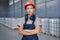 serious industrial woman engineer in hardhat standing in factory with arms folded