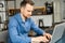 Serious intelligent male freelancer using laptop for work online sitting at the desk