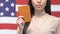 Serious lady showing passport against American flag, international cooperation