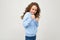 Serious lady teen girl in casual blue hoodie clenched her fists in front of her on a light studio background