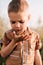 A serious little boy holds a snail in his hand in nature