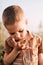 A serious little boy holds a snail in his hand in nature