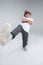 A serious little boy stands with arms crossed on chest and has one foot in front of him. On a gray background.