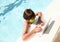Serious little boy using laptop in swimming pool
