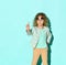 Serious little girl in jacket, blue t-shirt and beige jeans posing in flip-up glasses with her finger up asking to wait