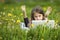 Serious little girl with laptop lying on green grass. Education.