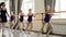 Serious little girls are learning sequence of ballet positions at ballet class with helpful teacher. Spacious light