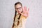 Serious long hair tweens girl in glasses pulling hand towards camera on white wall background