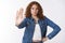 Serious-looking assertive curly-haired young girl show palm stop gesture hold hand waist confident look camera warning