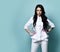 Serious-looking brunette woman doctor, nurse, cosmetologist in stylish uniform is standing with her hands on her hips