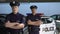 Serious male officers standing with hands crossed against police car background