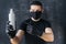 Serious Man in a black protective mask and gloves holds an antiseptic in his hands and points to it. Prevention of coronovirus and