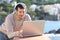 Serious man with headphones uses a laptop in a balcony