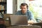 Serious man using a laptop with headphones in a bar