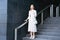 Serious mature businesswoman in elegant dress standing on stairs in front