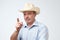 Serious mature hispanic man in cowboy hat showing index fingers up, giving advice or recommendation