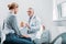 serious mature male doctor pointing at pills to female patient at table