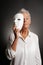 Serious mature woman revealing face behind mask